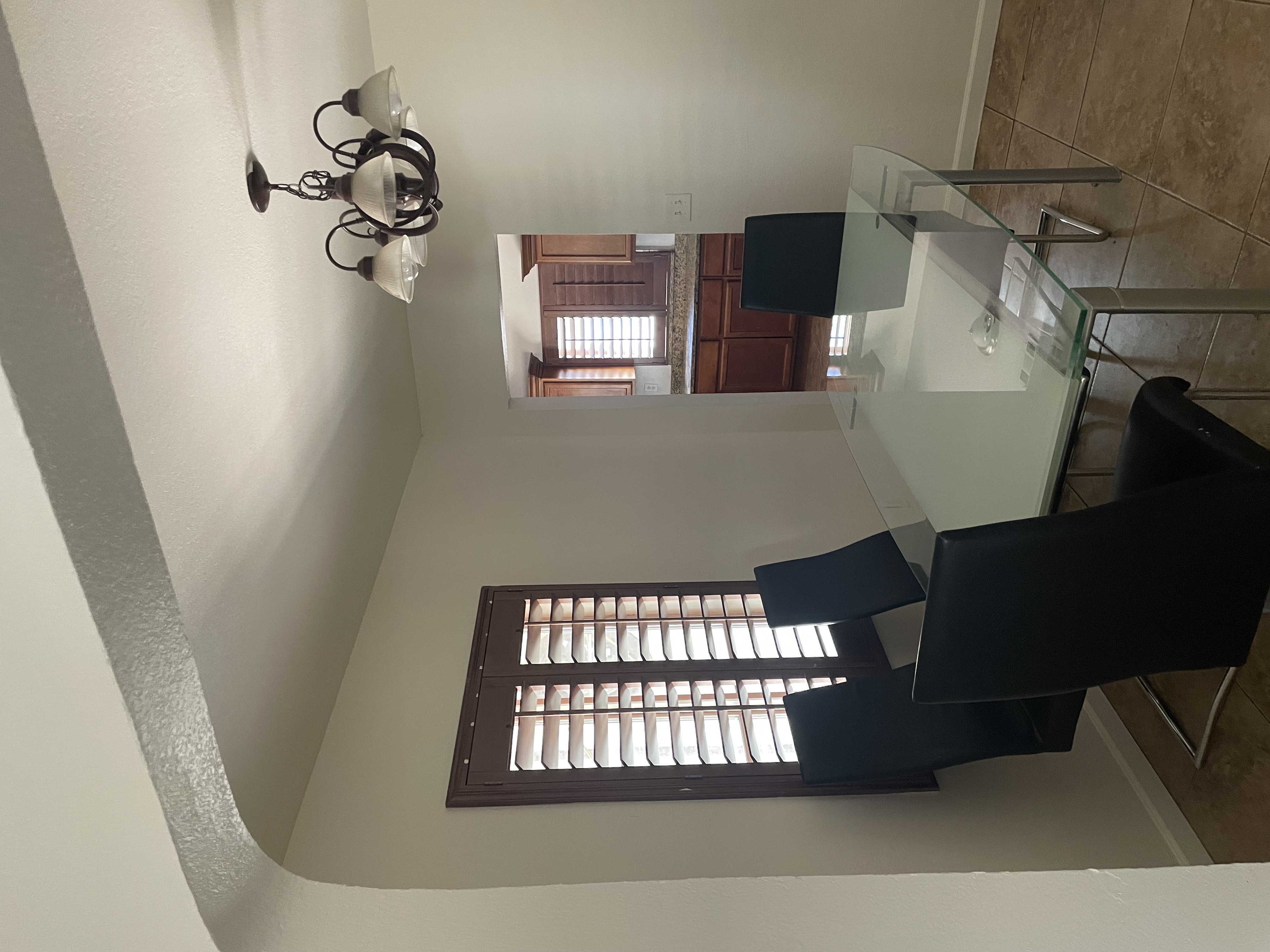 Dining room with a window, glass table, and four black leather chairs.